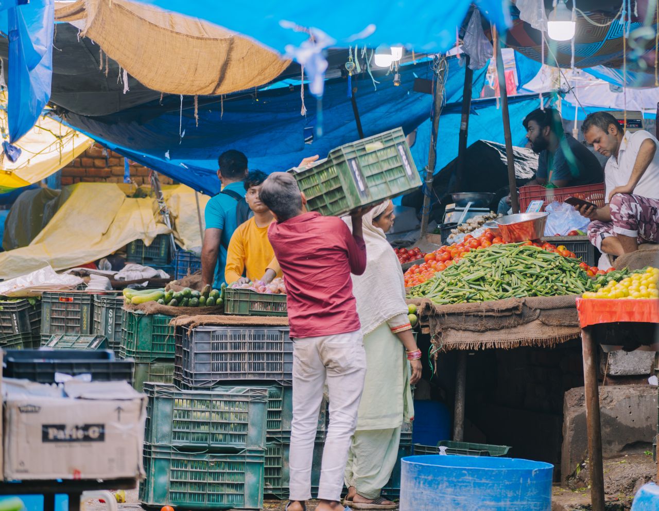 gallery-3 A vibrant market scene showing vendors and shoppers, surrounded by fresh produce and colorful stalls.