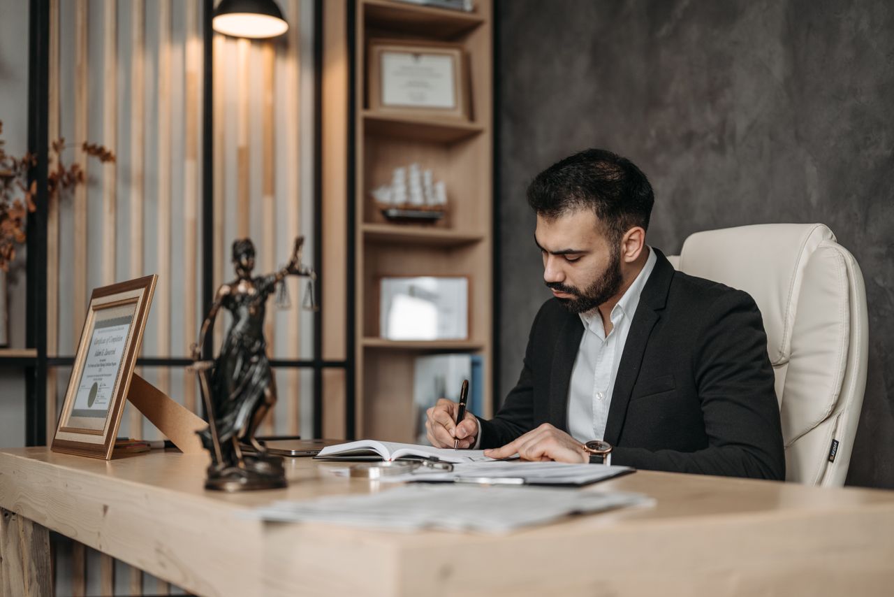 why-choose-us A focused lawyer in an office setting writing and reviewing legal documents, symbolizing expertise and professionalism.
